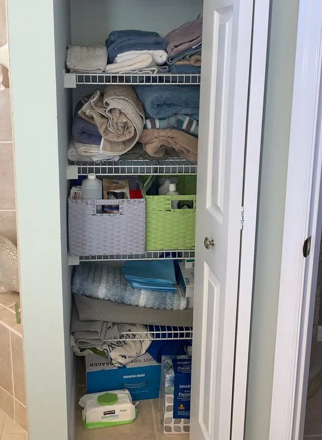 A linen closet with towels piled on the shelves